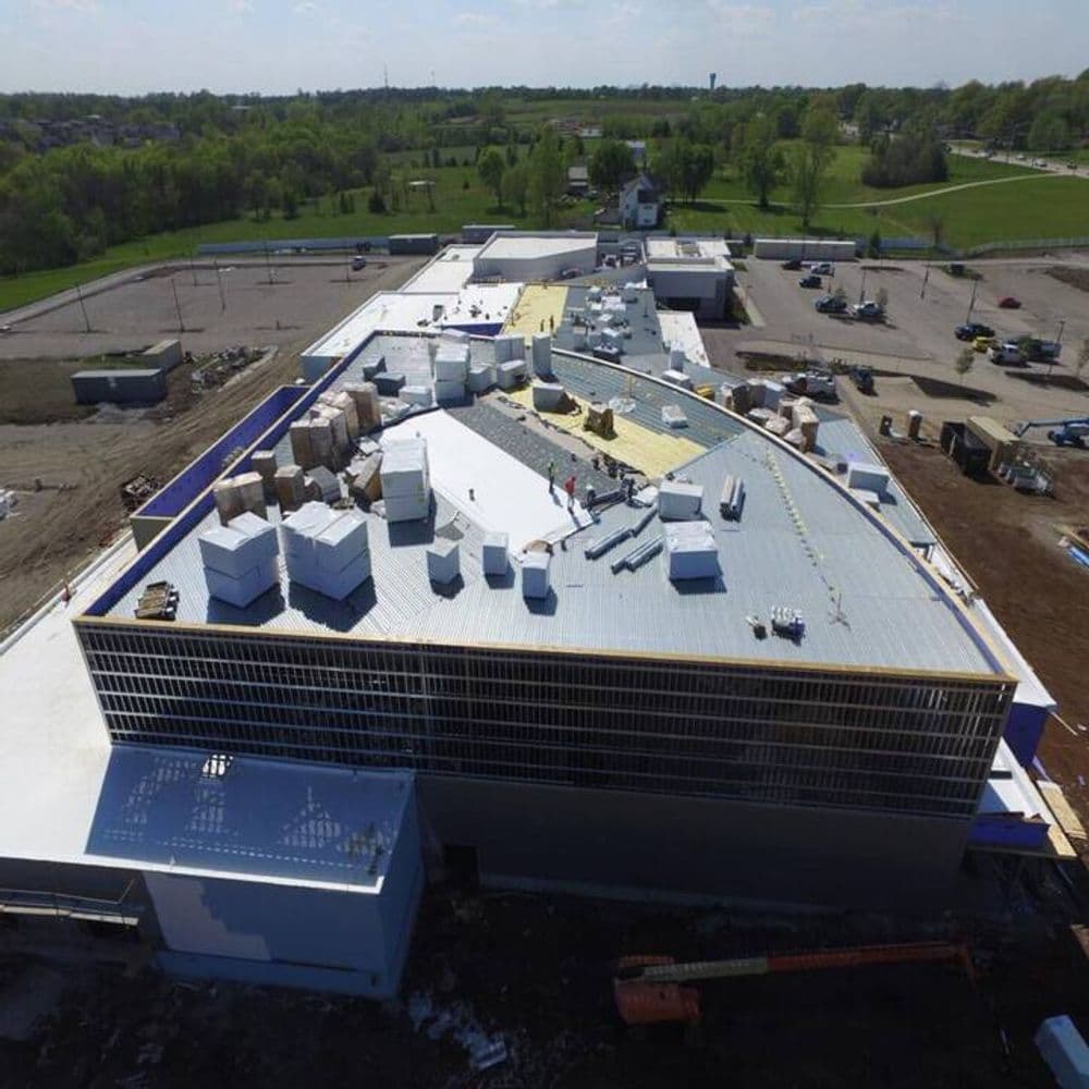 Aerial view of a commercial building under construction with workers on the roof.
