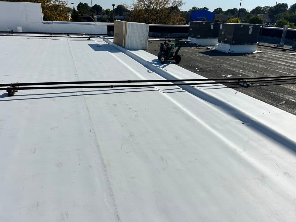 Flat commercial roof with a utility cart and equipment, showcasing rooftop maintenance area.
