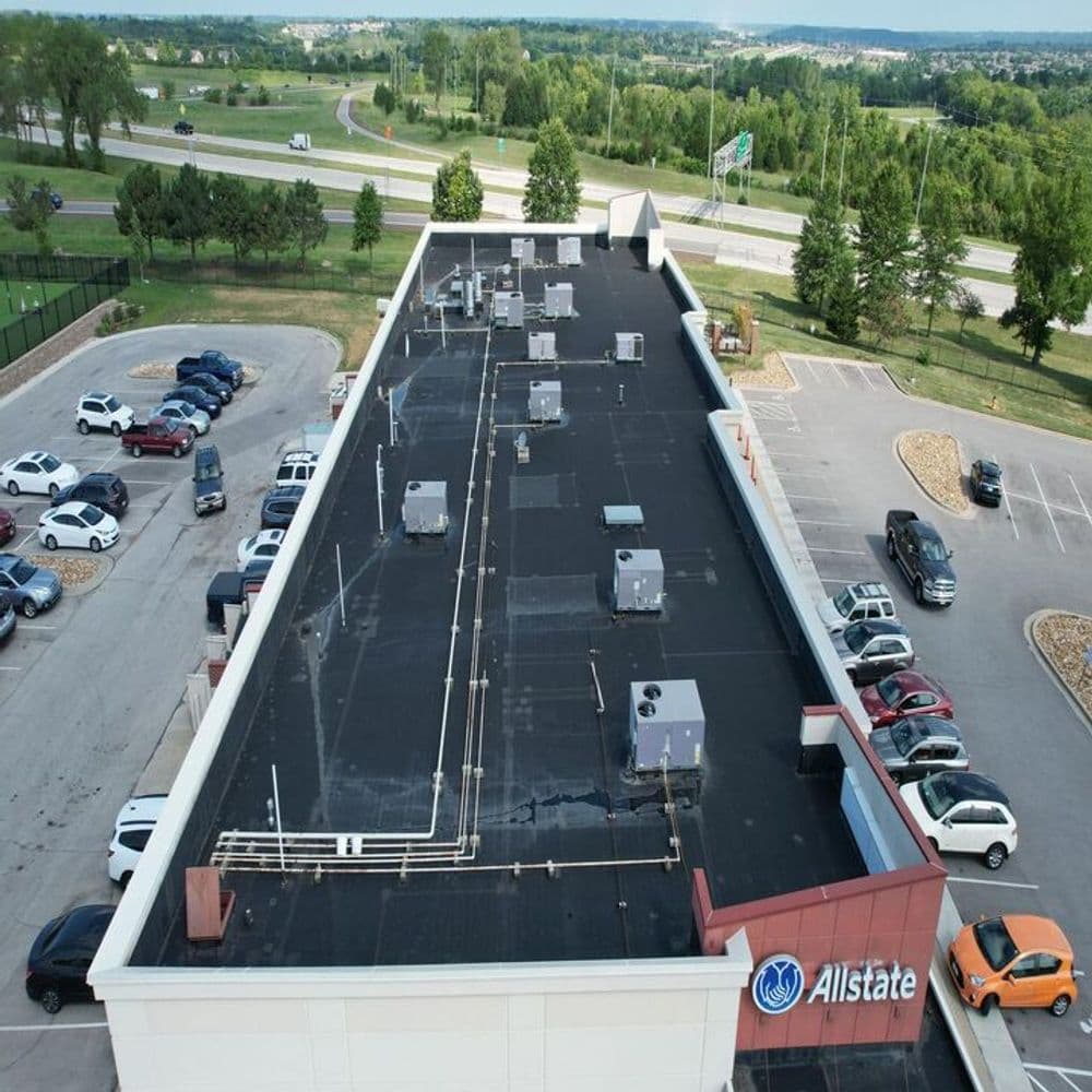 Aerial view of Allstate building rooftop with HVAC units and parking lot in the foreground.