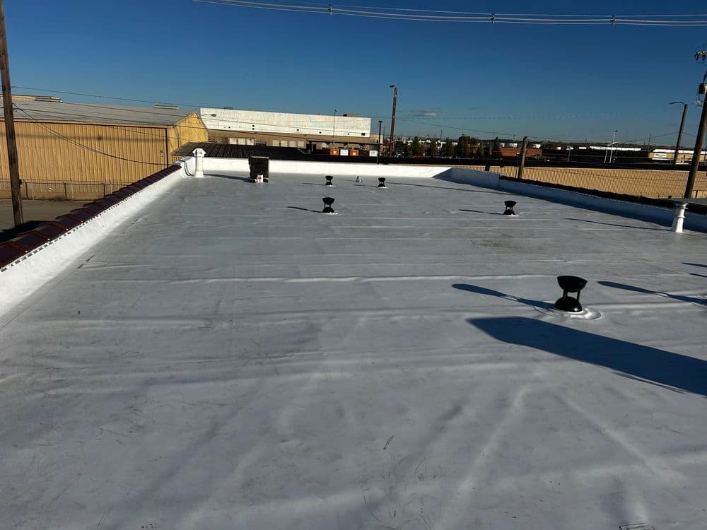 Flat commercial roof with ventilation pipes and clear blue sky in the background.