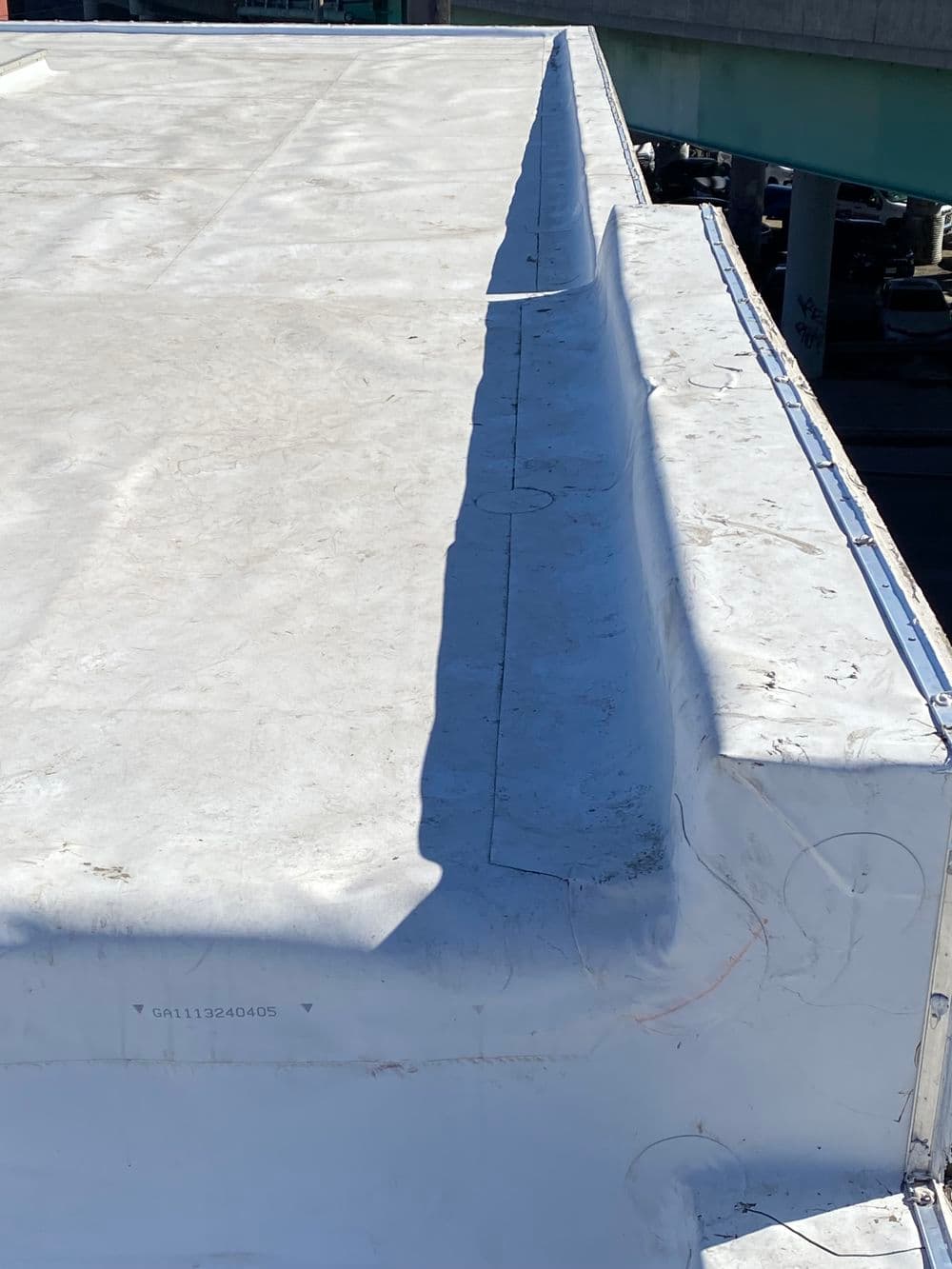 Flat rooftop with white membrane and clear sky, showcasing drainage edge detail.