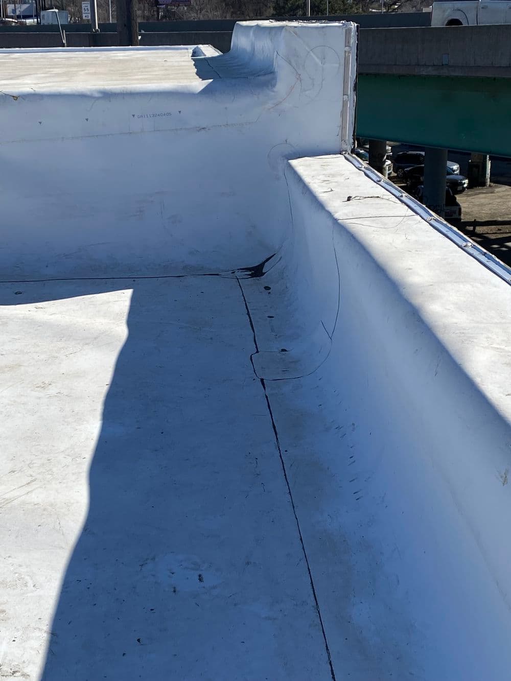 Flat white rooftop with seamless membrane and slight shadow from nearby structure.