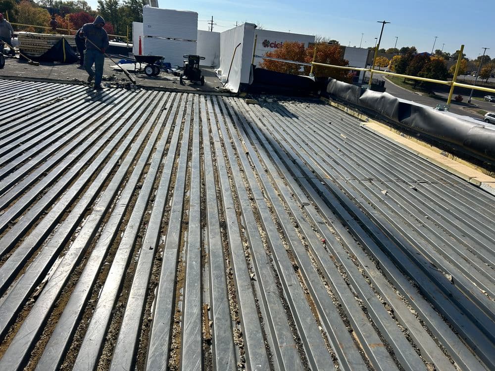 Workers installing a new roof on a commercial building with visible metal decking.