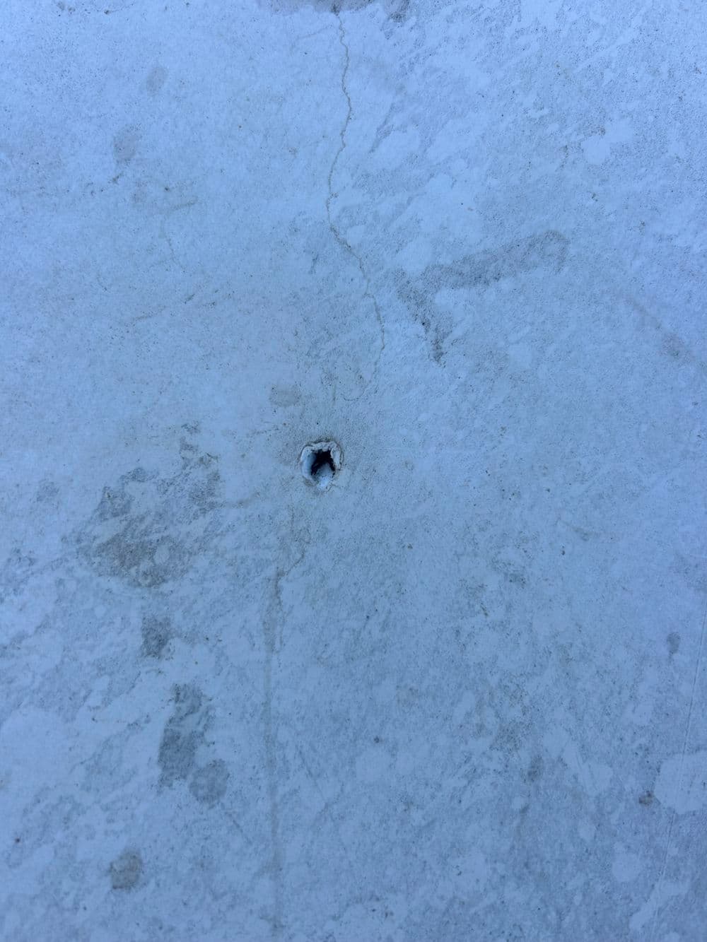 Close-up of a small hole in a concrete surface, displaying texture and surface imperfections.