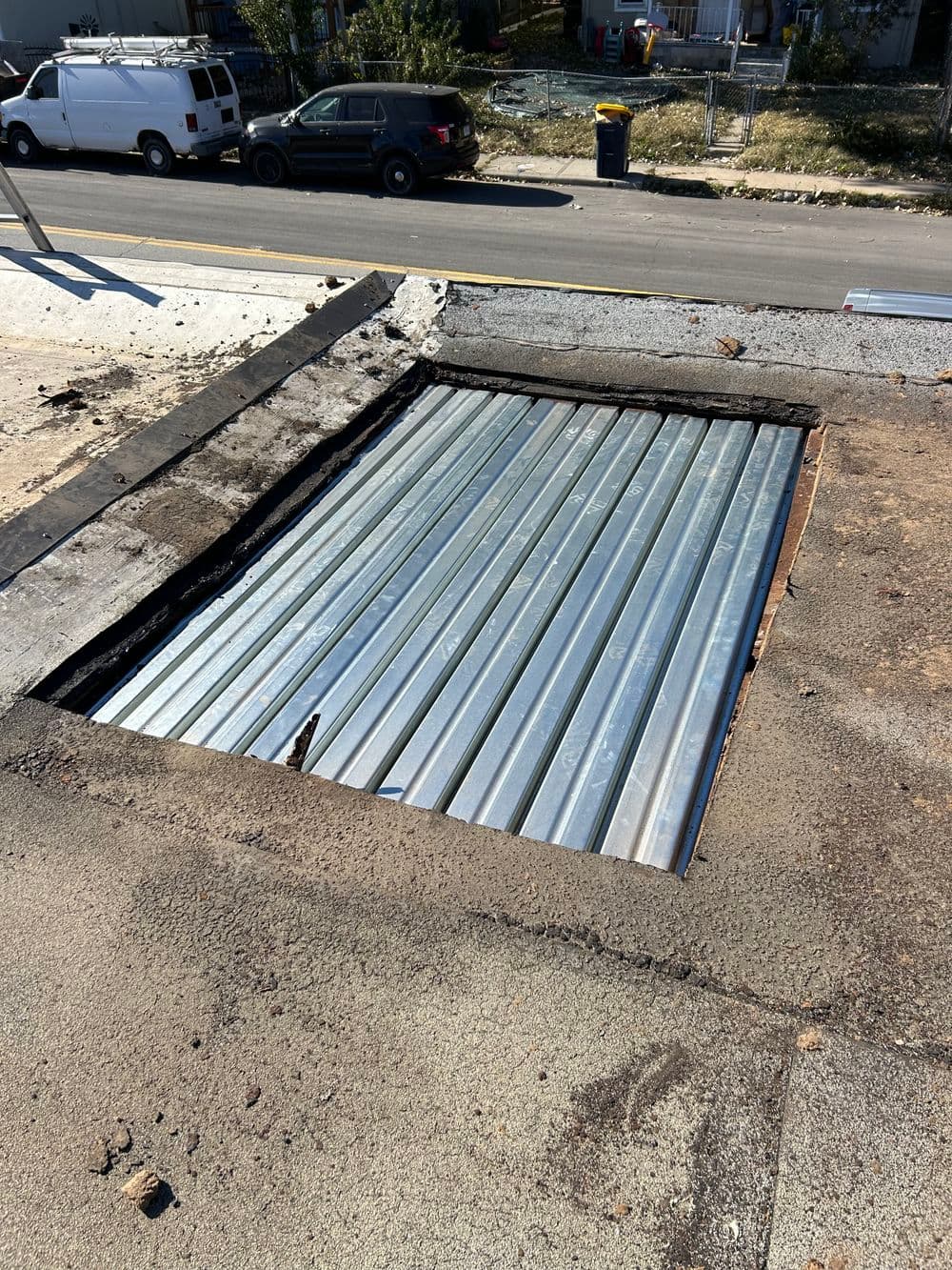 Open roof access with metal panels and surrounding debris in urban setting.